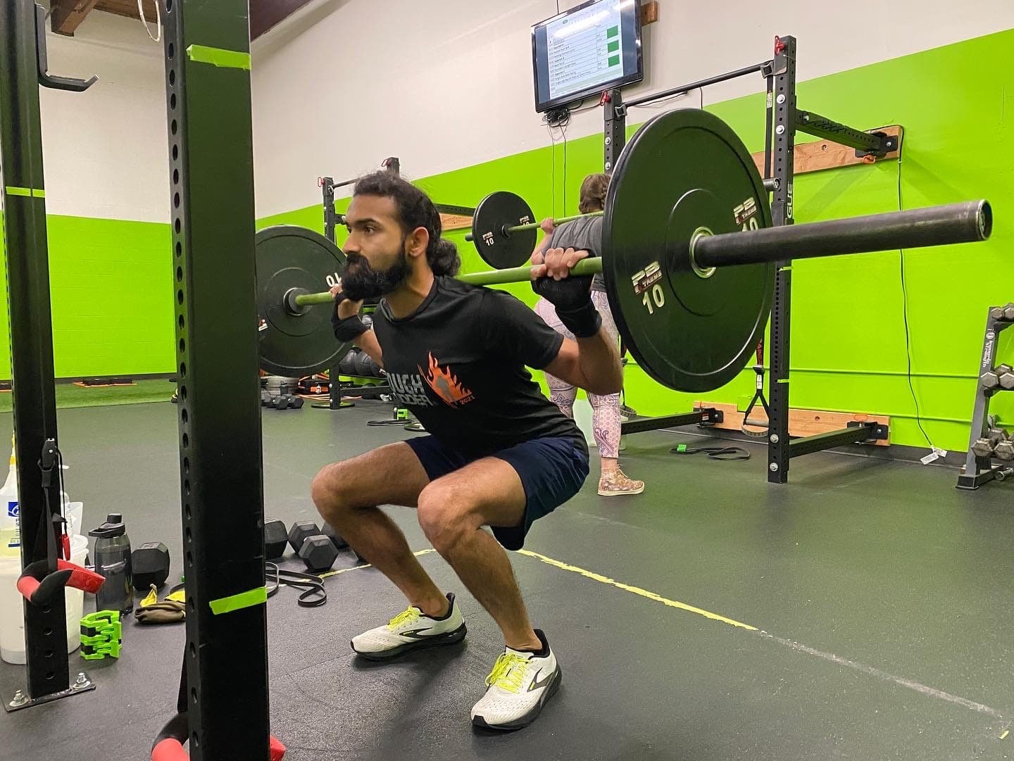 A client squatting a loaded barbell in the rack